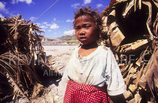 A young Aeta girl, born on the western flank of Mt. Pinatubo, stands before a palm leaf shelter, now her home on the Botolan River, Zambales.